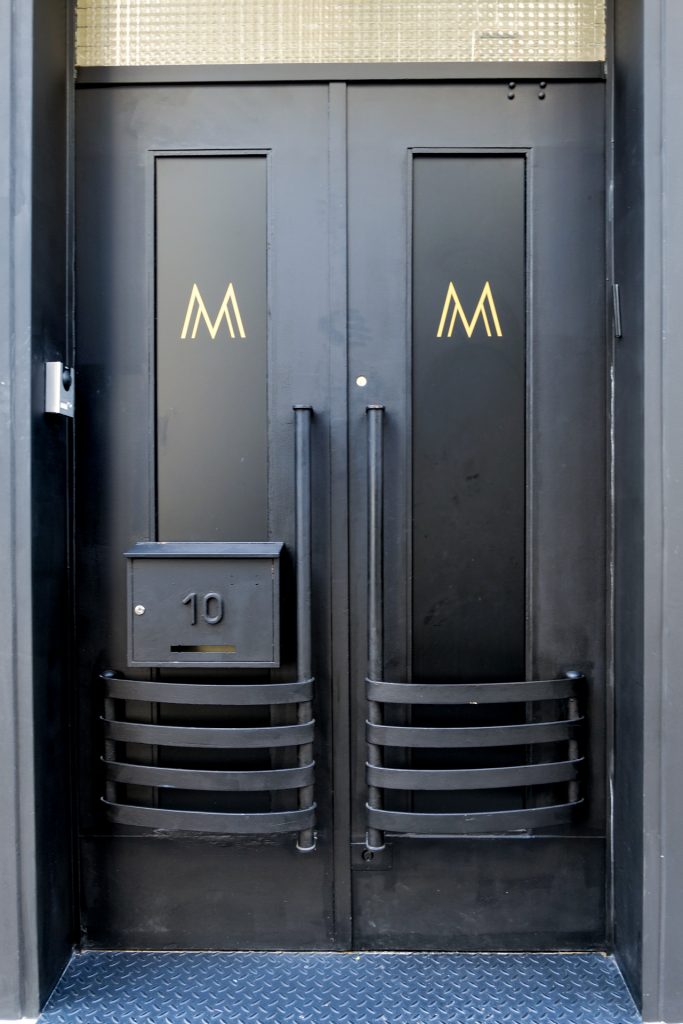 portes noires avec un M majuscule en dorées du centre médical esthétique Maison Marignan