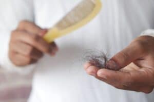Main tenant un peigne avec des cheveux tombés, signe d'une chute diffuse