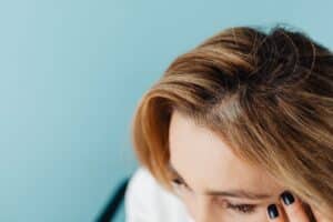 Femme qui examine la racine de ses cheveux au niveau du front