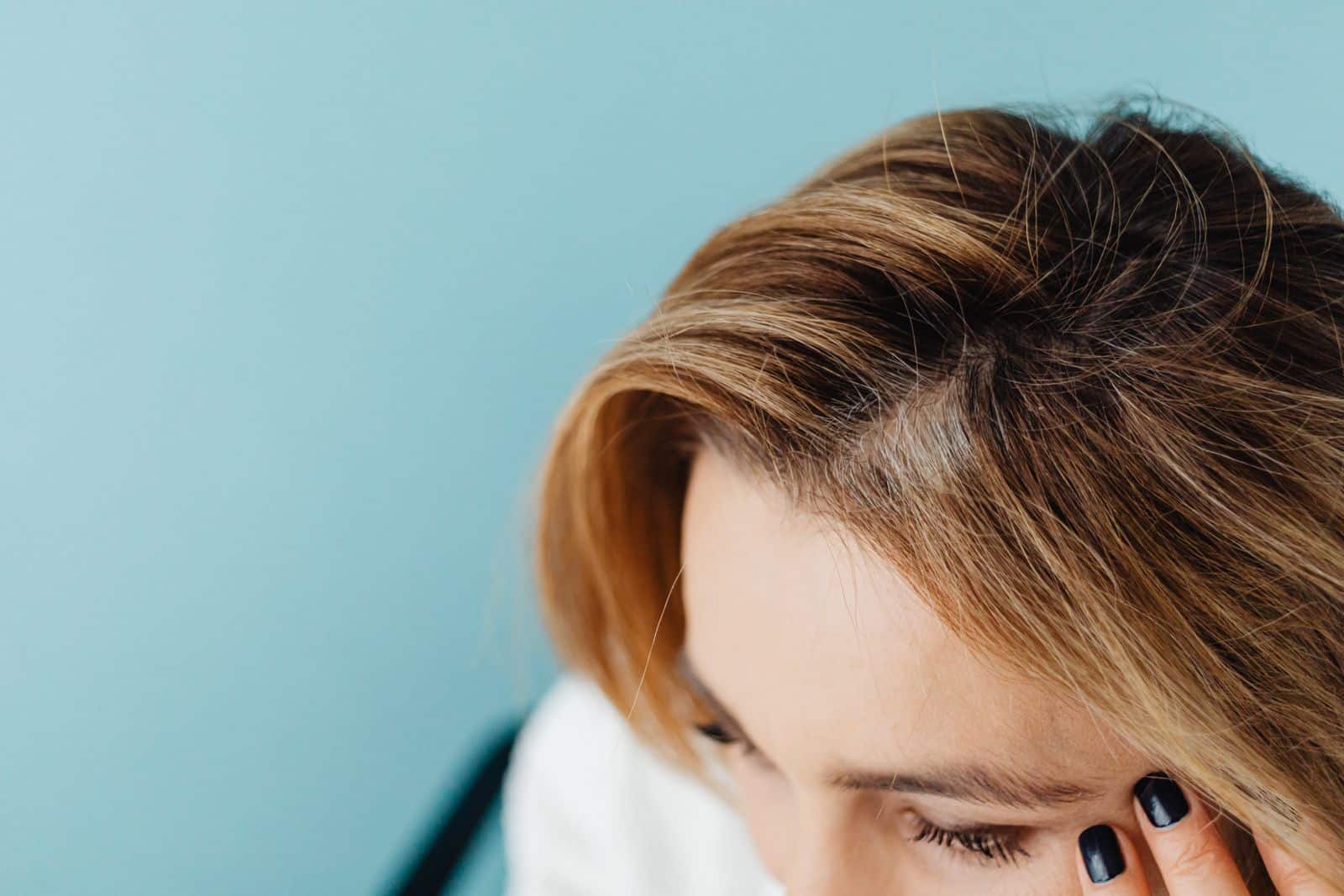 Femme qui examine la racine de ses cheveux au niveau du front
